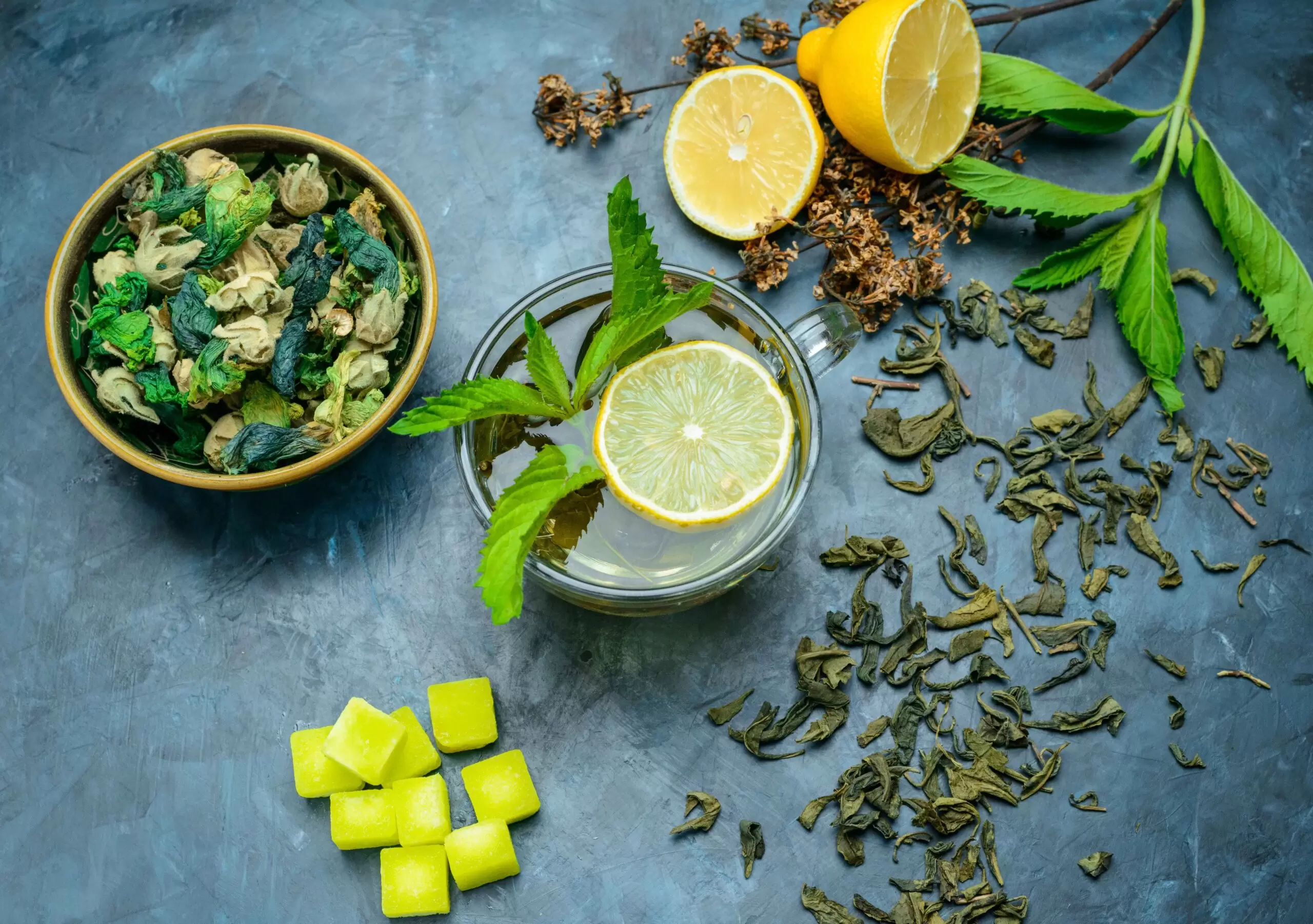 tea-cup-with-lemon-mint-dried-herbs-sugar-cubes-flat-lay-blue-surface_11zon-1-scaled